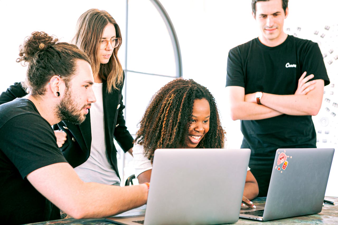 A diverse group of young professionals collaborating enthusiastically in a bright, modern workspace.